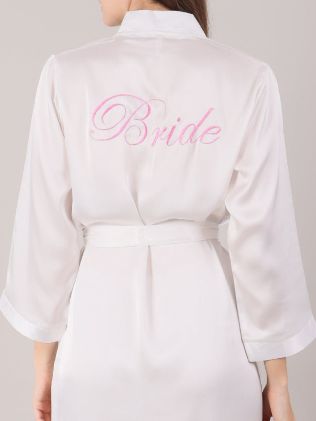 White satin robe with 'Bride' embroidered on the back, worn by a bride for her makeup shoot.